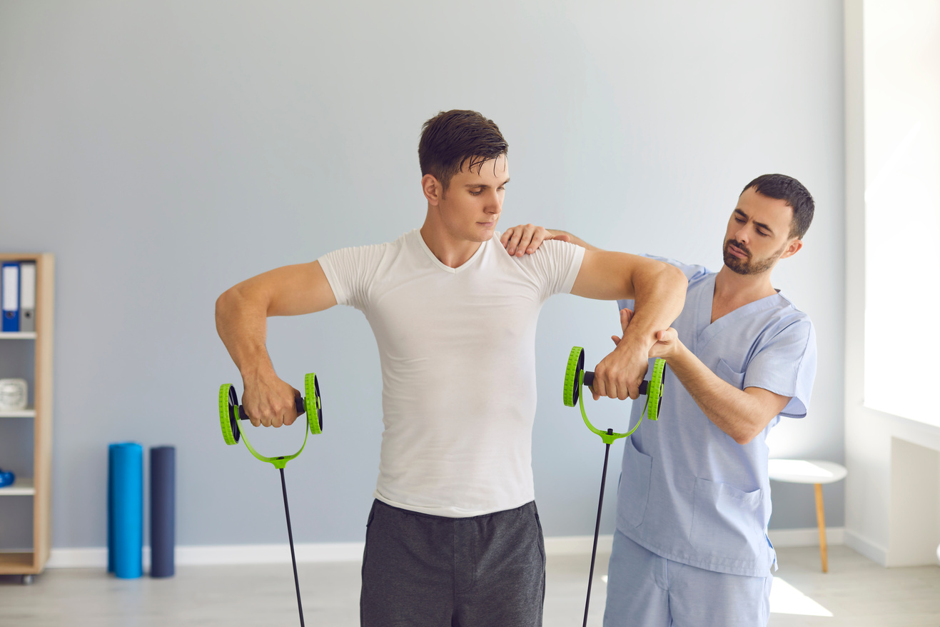 Physiotherapist Helping Young Male Athlete Recover after Sports Injury Using Special Resistance Band
